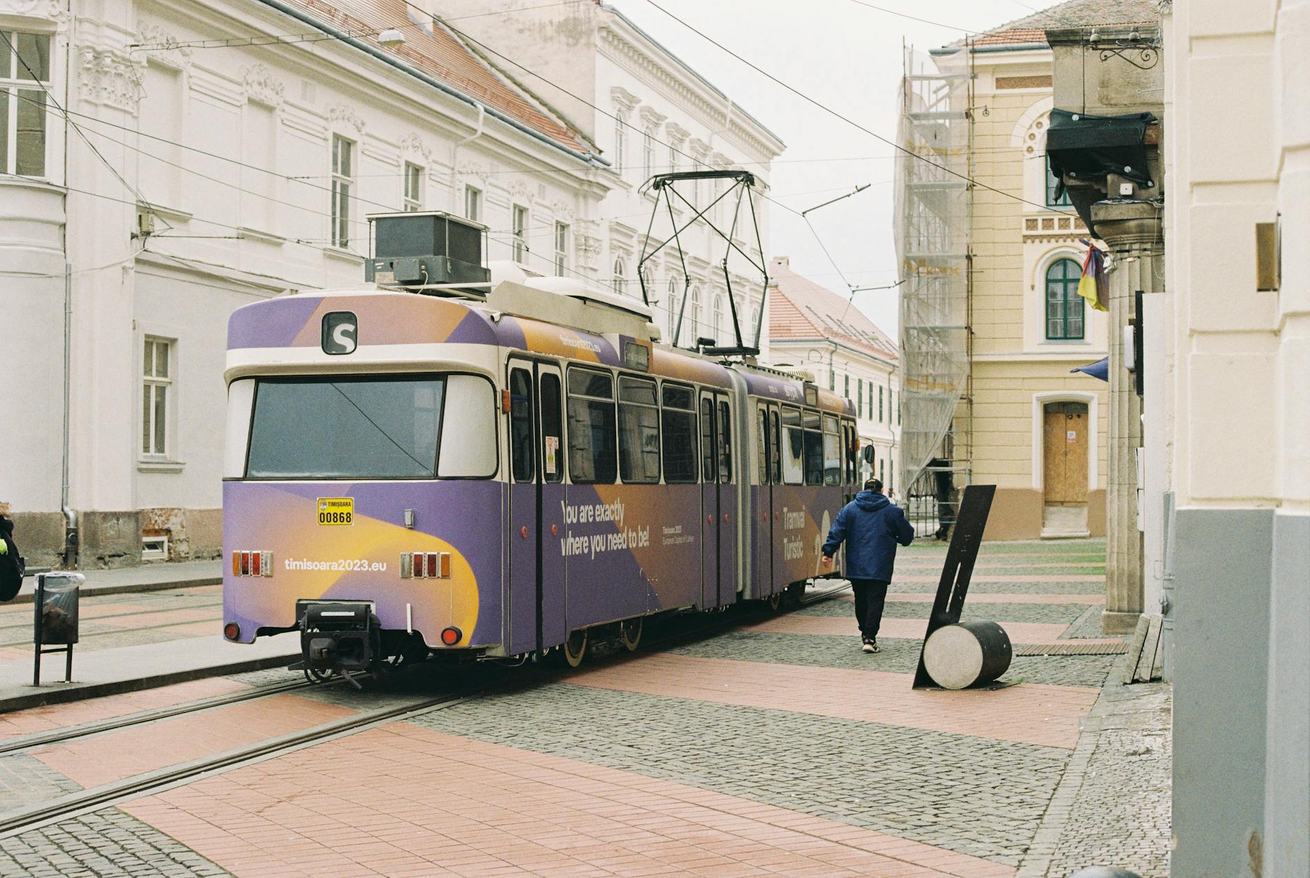 A tram travelling through a European city street with buildings on either side