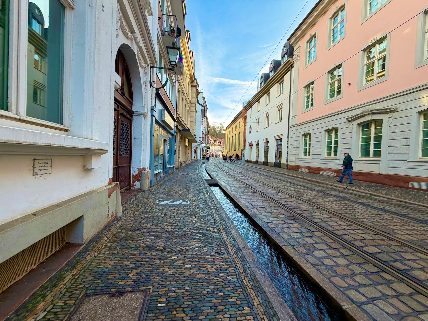 Pedestrians walking on a charming cobblestone European street with historic facades